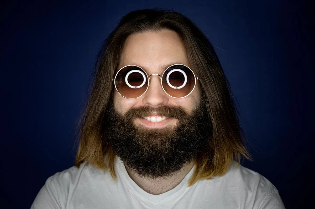 Deux reflets circulaires de ring light visibles dans les verres des lunettes
