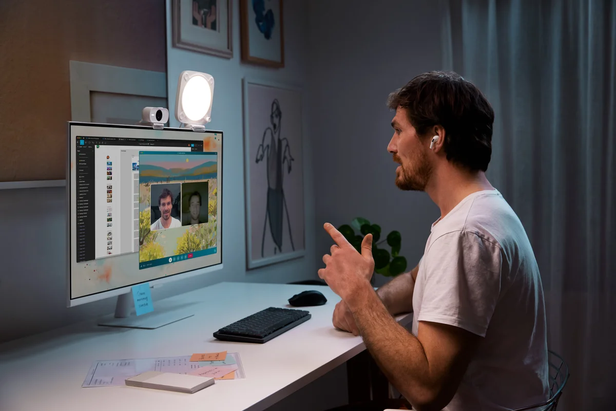 Key Light Neo blanc allumé sur un moniteur, à côté d’une webcam, dans une scène de visio officielle Elgato