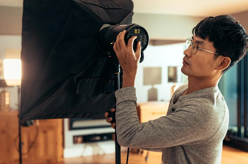 Une personne ajuste une lampe équipée d’une softbox